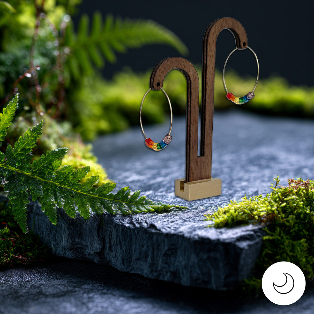 Pride rainbow earrings on a wooden stand against a natural background