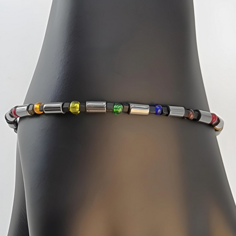 Colorful hematite pride bracelet, with smoky grey cylinder hematite beads alternating with clusters of matte black and translucent rainbow Czech glass beads.