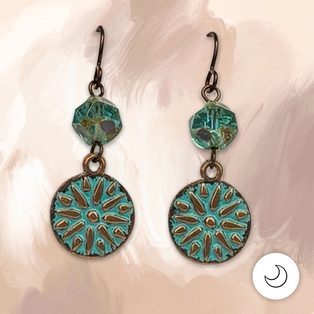 A sunburst medallion washed in verdigris patina hangs beneath a faceted aqua Picasso glass bead, all on hypoallergenic niobium hooks. They’re earthy, a little old-world, and easy to wear every day. 1 5/8" long.