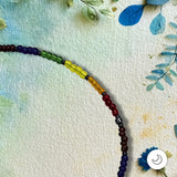 Detail view of a Pride rainbow beaded bracelet against a textured background with painted flowers