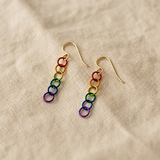 Rainbow chain link earrings with gold-filled ear wires on a beige fabric background