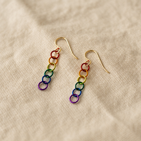 Rainbow chain link earrings with gold-filled ear wires on a beige fabric background