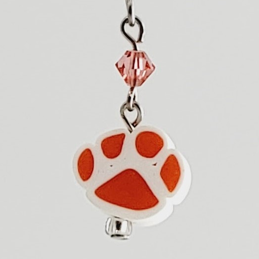Handmade, hypoallergenic earrings with orange paw prints on white clay and accented with peach crystals