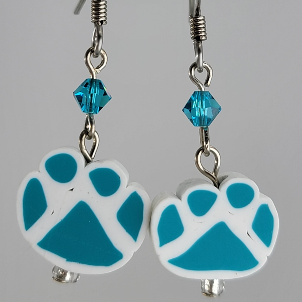 Earrings, blue paw prints on white paw print background. Blue crystal above each print. Ear wires are silver tone.