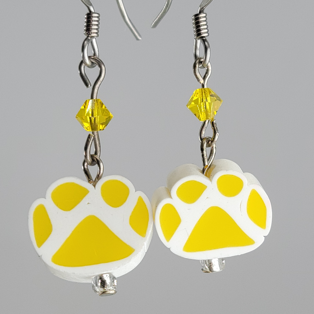 Earrings, yellow paw prints on white paw print background. Yellow crystal above each print. Ear wires are silver tone.