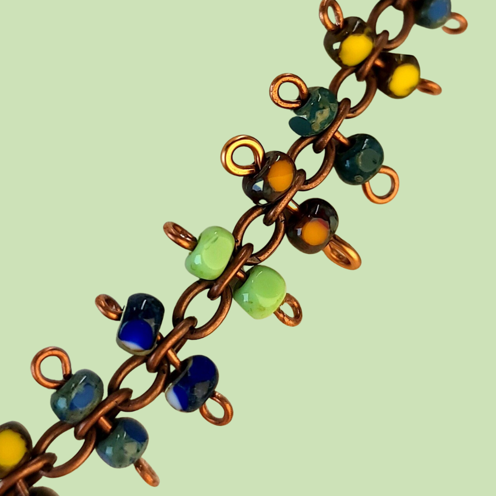 Brightly colored necklace with Picasso glass in greens, yellows, blues, and reds. Each station is a figure eight with bead at either end.
