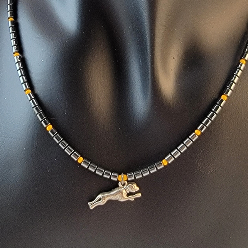 Handmade beaded necklace with pewter running dog pendant, hematite cylinder beads, and marigold accent beads. 