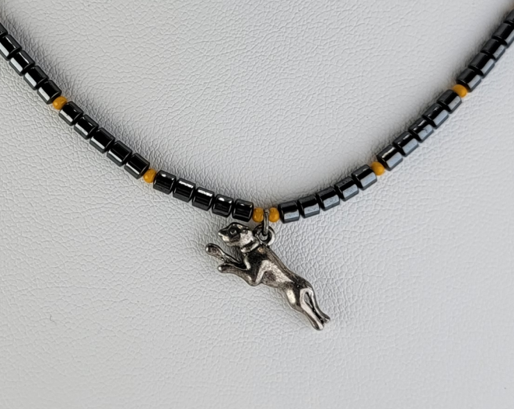 Handmade beaded necklace with pewter running dog pendant, hematite cylinder beads, and marigold accent beads. 