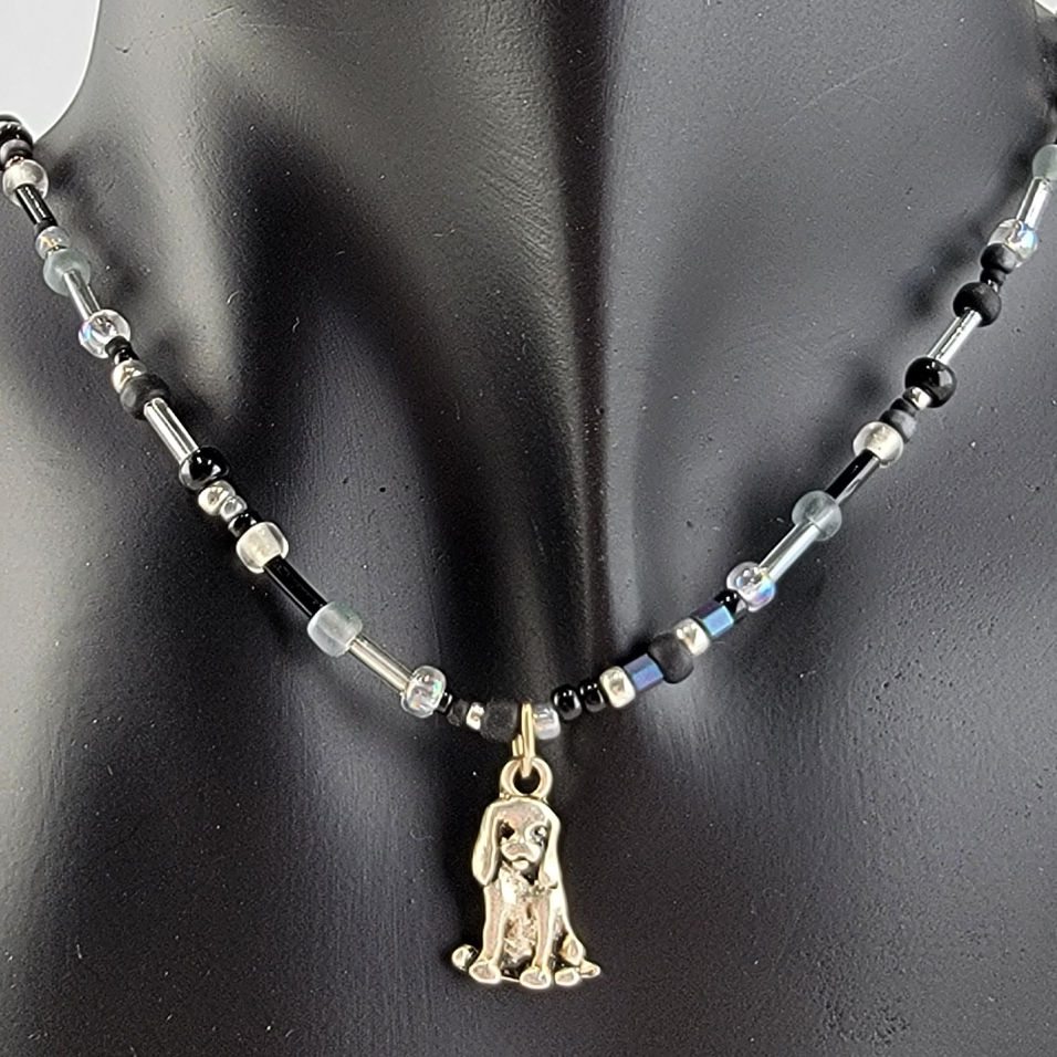 Handmade beaded necklace with pewter sitting dog pendant and black, silver, clear, and grey beads