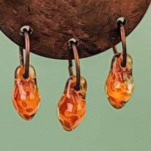 Handmade Boho earrings with amber colored Picasso glass dangling from rich brown wooden pendants. Ear wires are hypoallergenic niobium. Total earring length is 2 1/4".