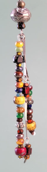Long, dangly, colorful Boho earrings featuring three drops filled with richly-colored Picasso glass beads and silver-colored accents. 