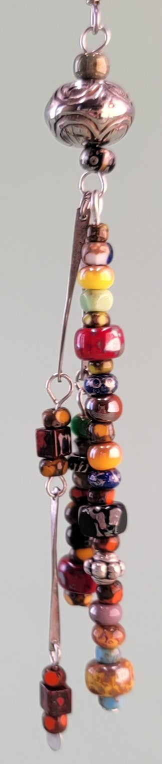 Long, dangly, colorful Boho earrings featuring three drops filled with richly-colored Picasso glass beads and silver-colored accents. 