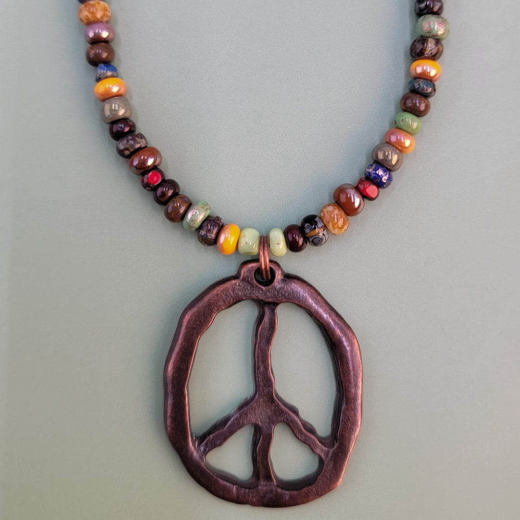 Handmade Boho necklace with antiqued copper peace sign and Picasso glass beads in a multitude of colors. 