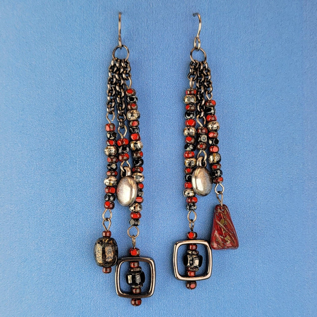 Handmade Boho style earrings with a retro feel. Red, black, and gray Picasso glass along with a bit of pewter, and gleaming black square frames. These beauties are 3 1/2" long with hypoallergenic niobium ear wires.
