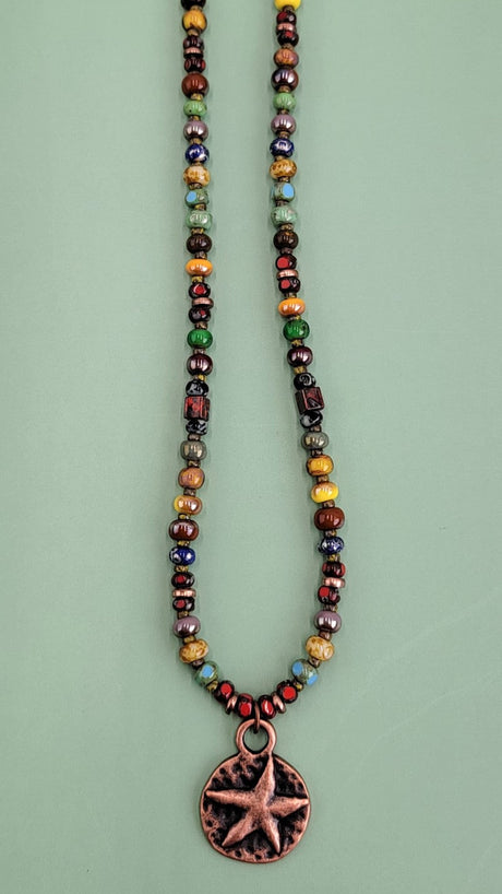 Handmade Boho necklace featuring a rustic antiqued copper sea star and an array of bright Picasso glass beads in multiple colors. Coastal-inspired artisan jewelry for a touch of seaside elegance.