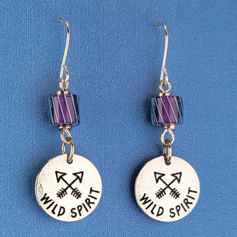 Handmade earrings with wild spirit crossed-arrows pendants and gorgeous purple and blue American glass. Hypoallergenic stainless steel ear wires. Total earring length is 1 3/4" long.