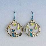 Handmade cat and star earrings including blue enamel cat on blue background looking at green enamel stars