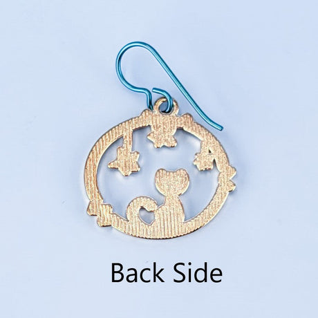 Handmade cat and star earrings including blue enamel cat on blue background looking at green enamel stars